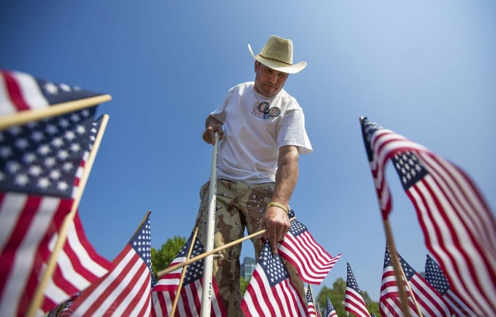 Carlos Arredondo plants flags for the Massachusetts Heroes Fund flag garden on Wednesday. (Jesse Costa/WBUR)