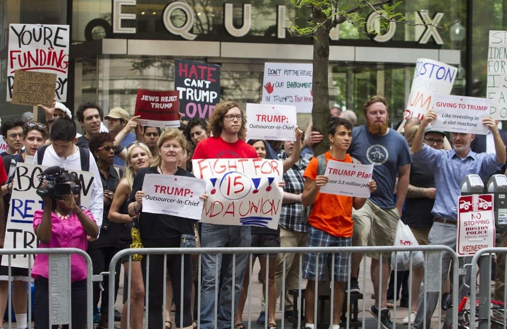 People gathered on Franklin Street hold signs reading "Hate Can't Trump Love" and "Giving to Trump: Like investing in a slot machine." (Joe Difazio for WBUR)