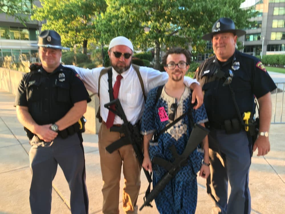 Ohioans Micah Naziri (middle left) and James Campbell (middle right) stand with officers from the Wisconsin State Patrol. Naziri and Campbell are carrying AR-15s. (Alex Ashlock/Here & Now)