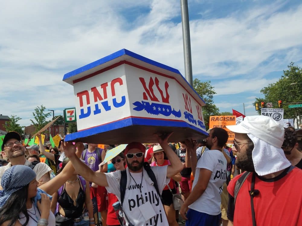Protesters in Philadelphia carry a red, white and blue casket labeled "DNC" through the streets. (Zeninjor Enwemeka/WBUR)