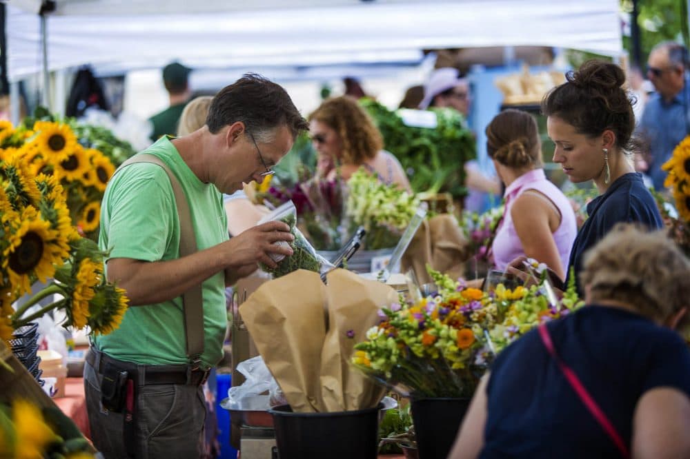 Siena Farms owner Chris Kurth bags up some greens for a patron at the Siena Farms stand at the Copley Square Farmers Market. (Jesse Costa/WBUR)