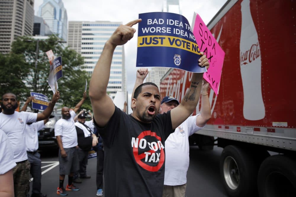 With summer here, Americans are swigging gallons of soda. The Philadelphia City Council began the season on a different tack: by voting to tax it. Pictured here, opponents of the proposed sugary drink tax demonstrate outside City Hall in Philadelphia on June 8, before the vote passed to instate the tax. (Matt Rourke/AP)