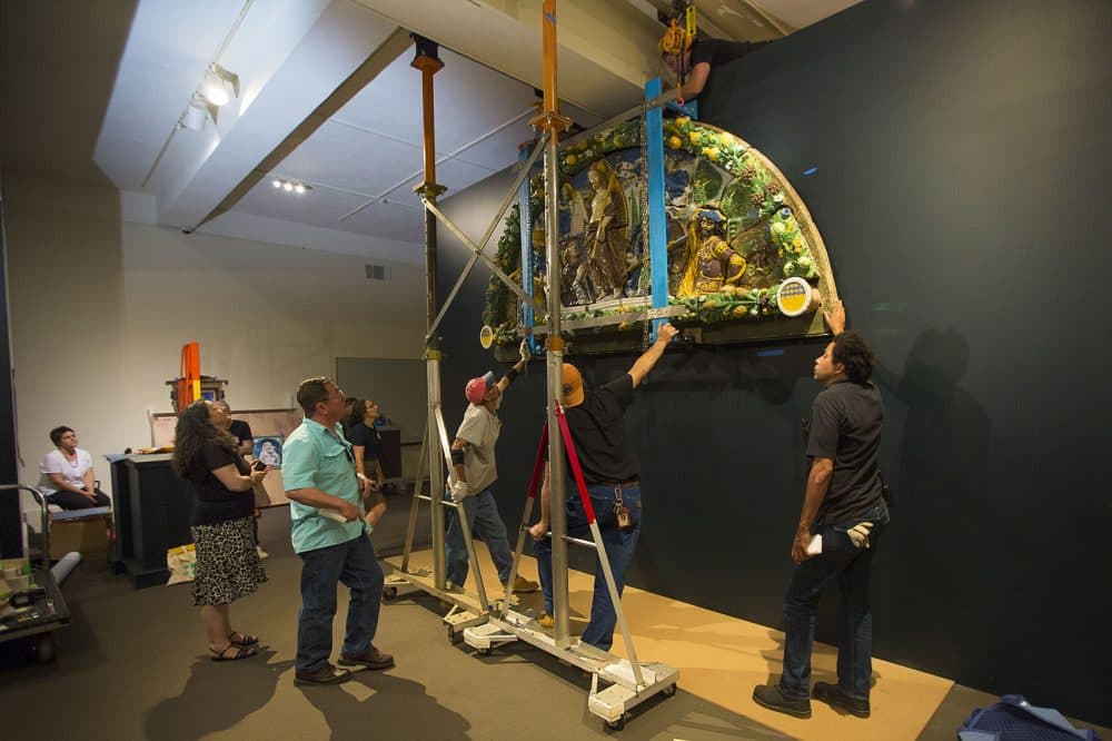 Once lifted to the top of the display wall, MFA senior curator Marietta Cambareri and engineer Dante Vallance watch workers begin to mount the piece to the wall. (Jesse Costa/WBUR)