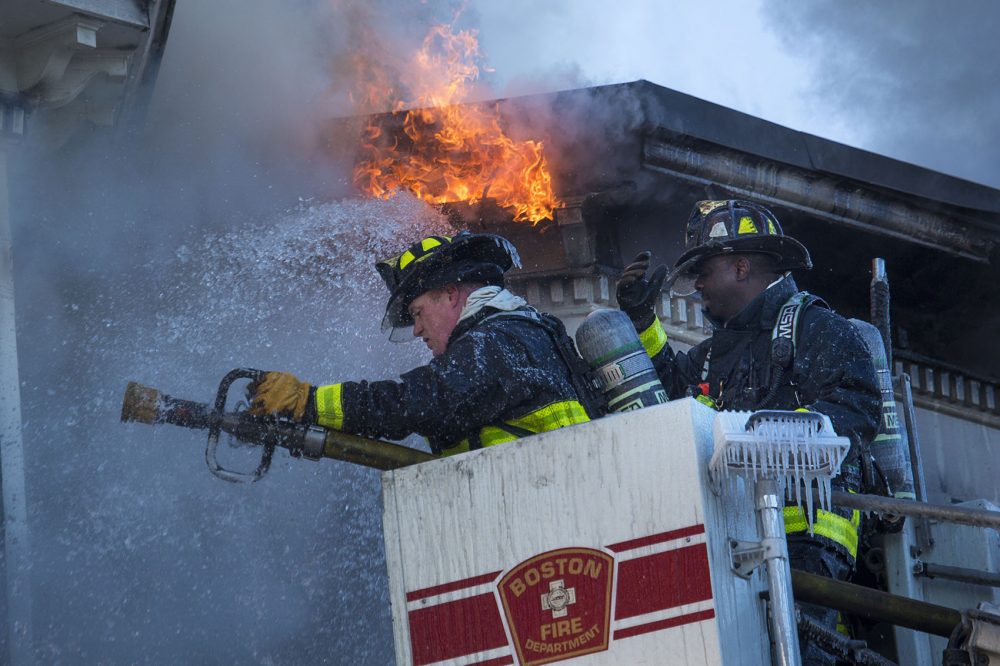 Icicles form around the Boston firefighters' equipment as they battle the fire in Charlestown in frigid conditions. (Jesse Costa/WBUR)