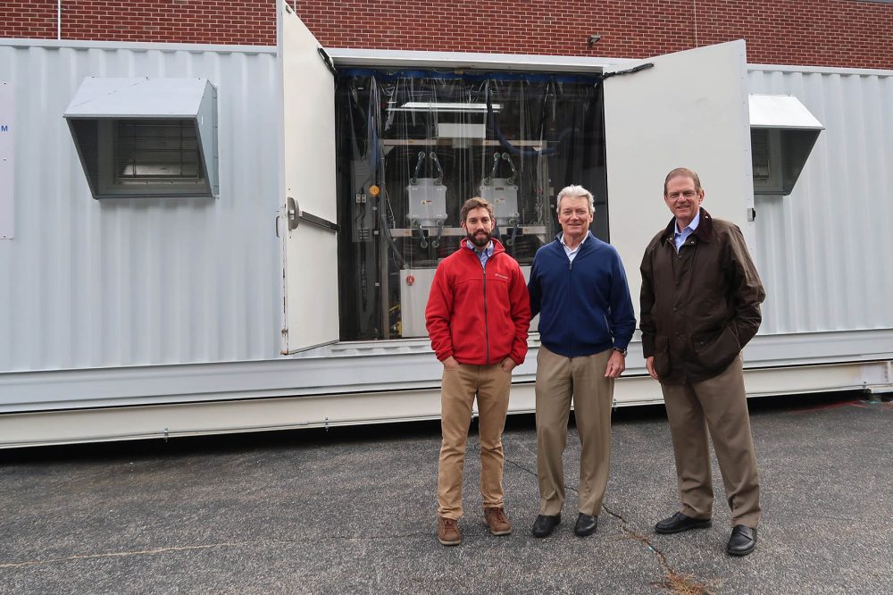 McNeely, CEO David Vieau and Director of Business Development Jonathan Milley stand in front of the Vionx Energy vanadium redox flow battery. (Bruce Gellerman/WBUR)