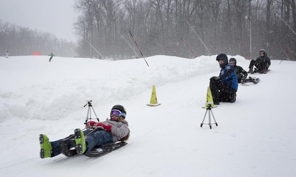 U.S. Olympian Gordy Sheer, kneeling, sends a potential luger across the start line. (Robin Lubbock/WBUR)