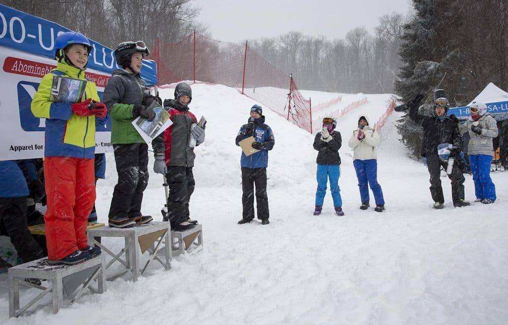 Ten-year-old William Watson, left, smiles as former U.S. Olympic luger, Gordy Sheer, announces the winners of the day's boys luge racing at Wachusett Mountain. (Robin Lubbock/WBUR)