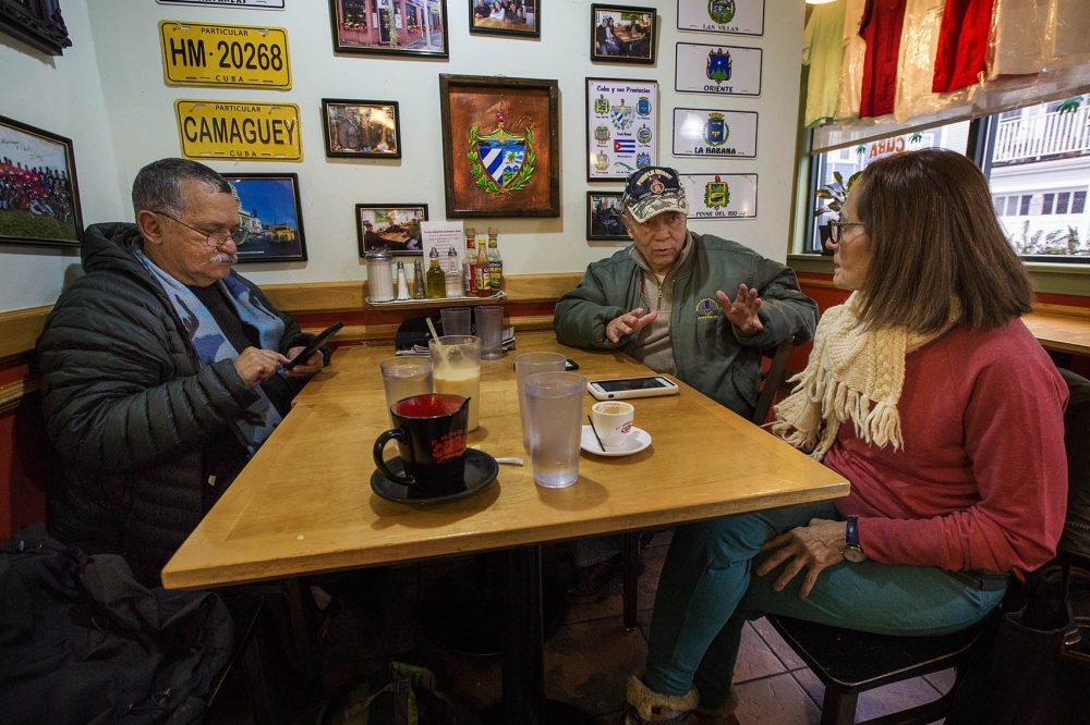 From left to right, Jaime Rodriguez, Tony Molina and Mirna Lascano discuss the commutation of Oscar López Rivera at the El Oriental de Cuba restaurant in Jamaica Plain. (Jesse Costa/WBUR)