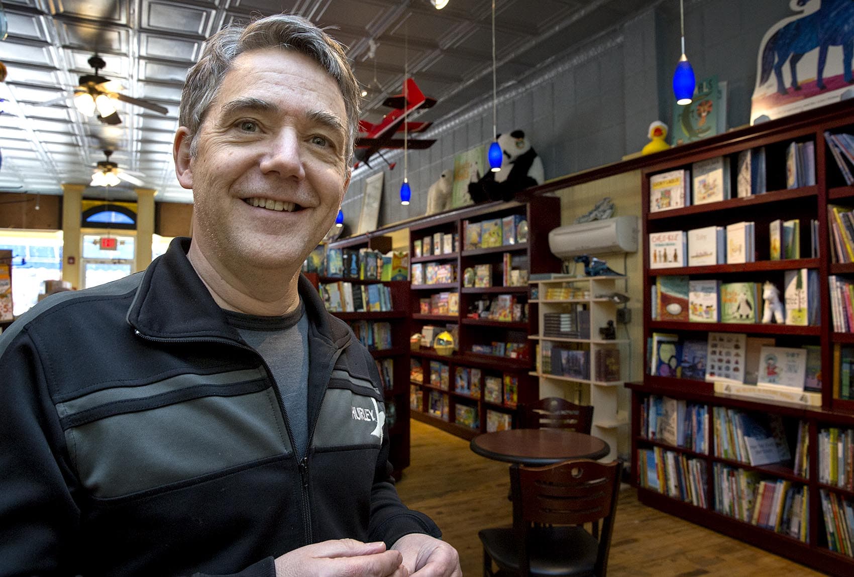 Peter H. Reynolds, owner of The Blue Bunny Bookstore in Dedham stands surrounded by books on the day Amazon also opened a bookstore in the town. He said independent bookstores are an endangered species and need to be supported so they can stick around. (Robin Lubbock/WBUR)
