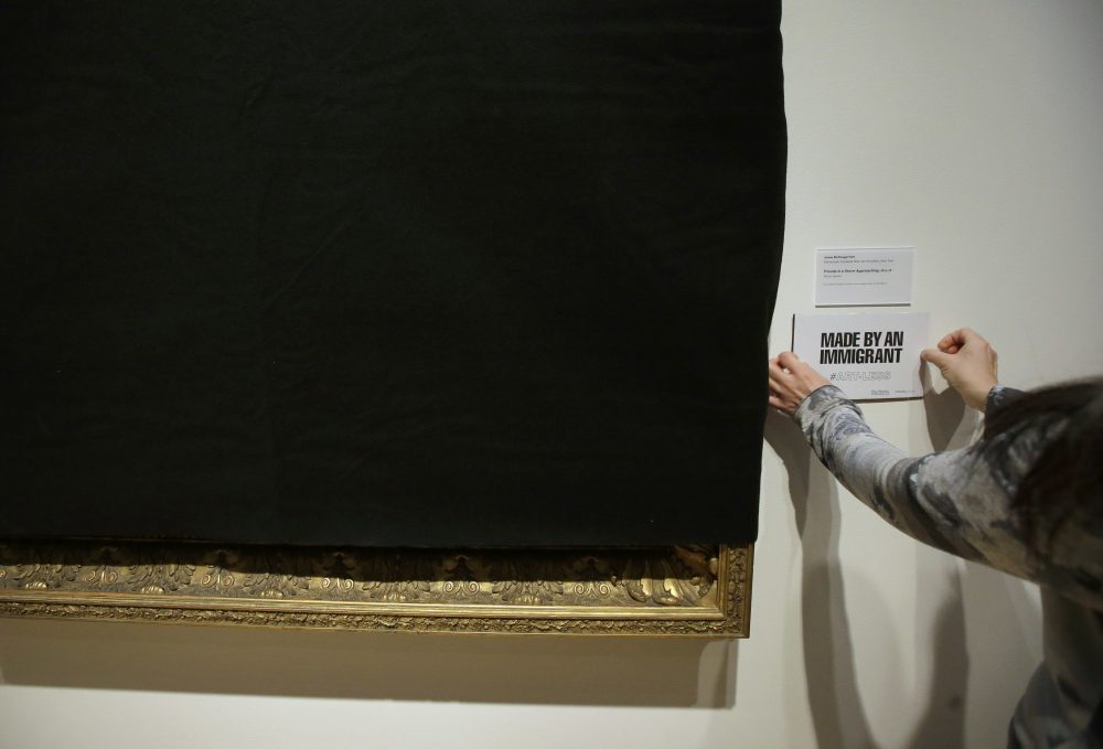 Davis Museum associate director Tsugumi Joiner places a placard near the covered painting "Friends in a Storm Approaching," 1875-1876, by Scottish-born artist James McDougal Hart on Thursday at the museum in Wellesley. (Steven Senne/AP)