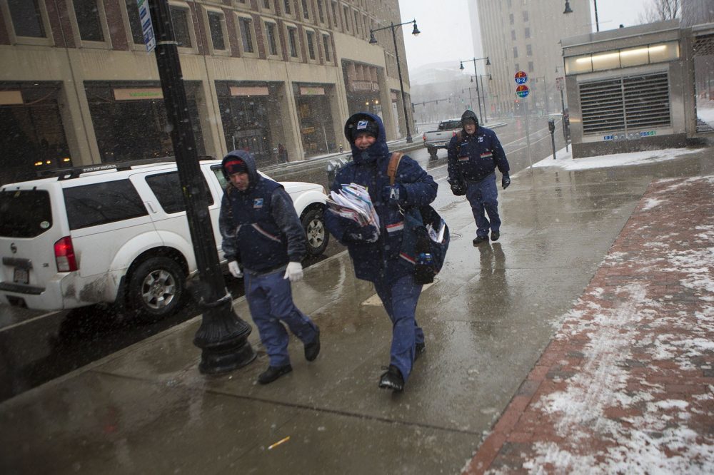 The blizzard didn't keep the mail from being delivered. Three mail carriers walked through City Hall Plaza. (Jesse Costa/WBUR)
