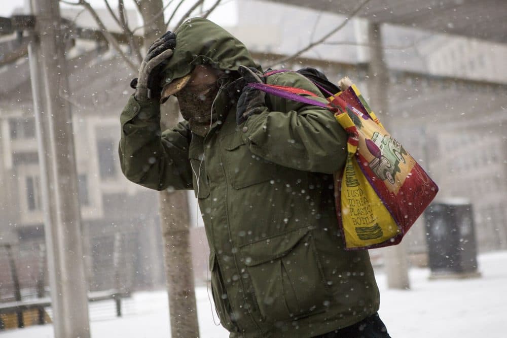 A man hid from the winds whipping through City Hall Plaza in Boston. (Jesse Costa/WBUR)