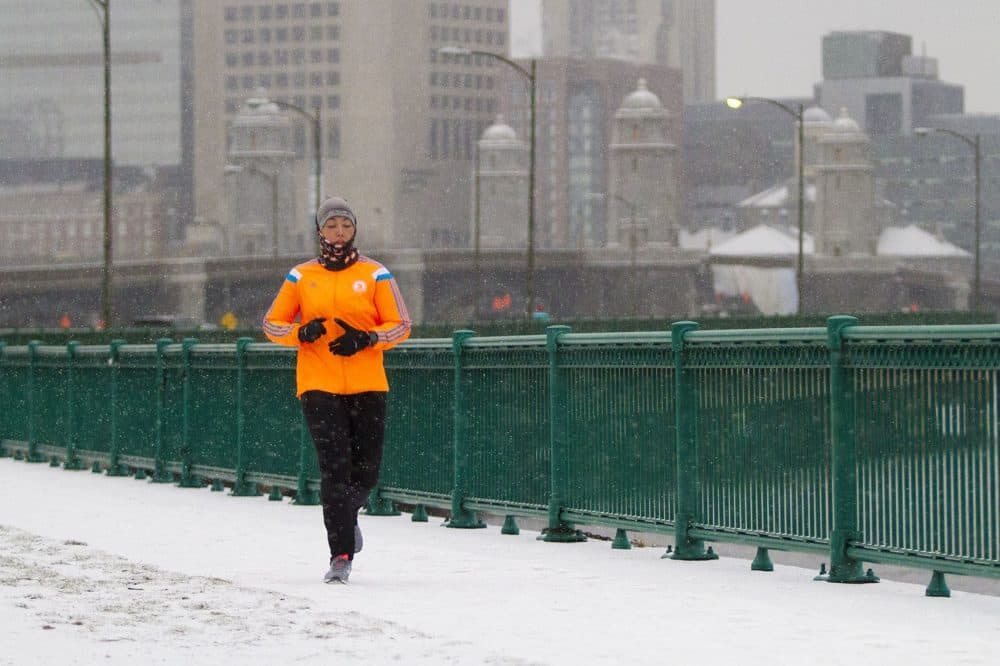 A runner made their way along on Memorial Drive as the snow began to fall. (Jesse Costa/WBUR)