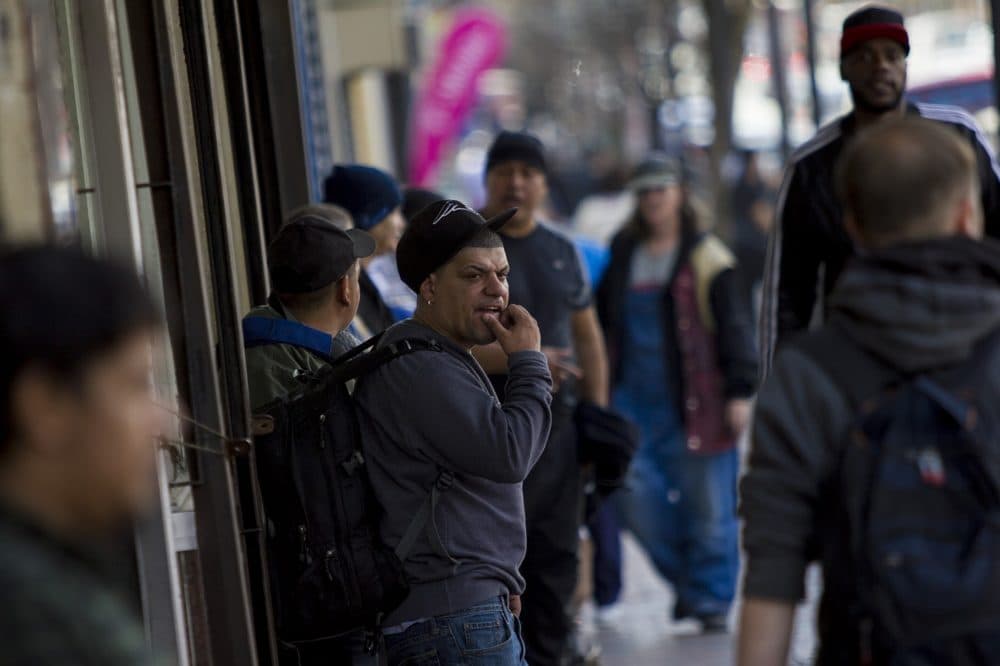 People bustle along Broadway in front of Full Service Laundry in Chelsea. (Jesse Costa/WBUR)