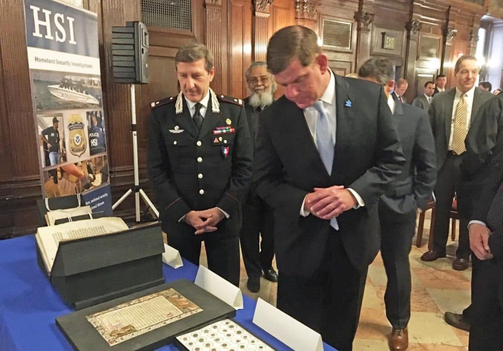 Boston Mayor Marty Walsh, right, and Gen. Fabrizio Parrulli of the Carabinieri, the Italian national police, look at the mistakenly stolen items the Boston Public Library returned to the Italian government during a repatriation ceremony Wednesday. (Anthony Brooks/WBUR)