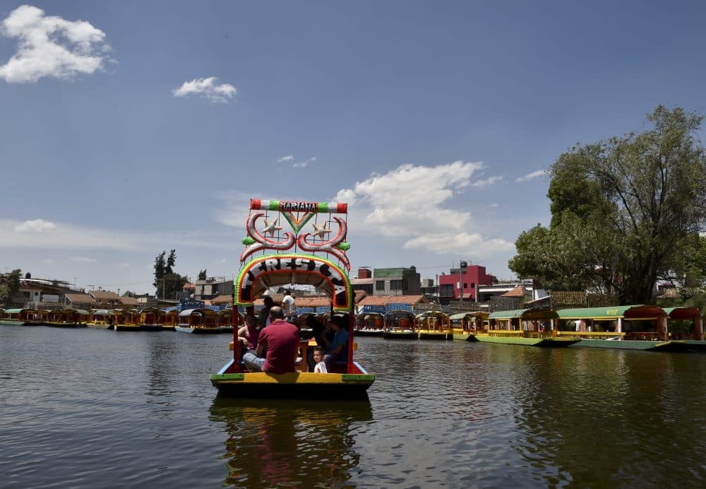 A rower and tourists are seen on board of a moored "trajinera," a traditional flat-bottomed river boat, at Xochimilco natural reserve in Mexico City on April 1, 2016. (Yuri Cortez/AFP/Getty Images)