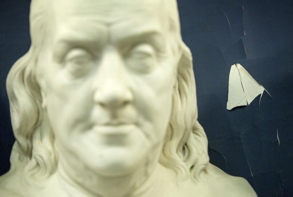 Paint peels away from cracked plaster behind the Benjamin Franklin bust in the Senate Chamber. (Robin Lubbock/WBUR)