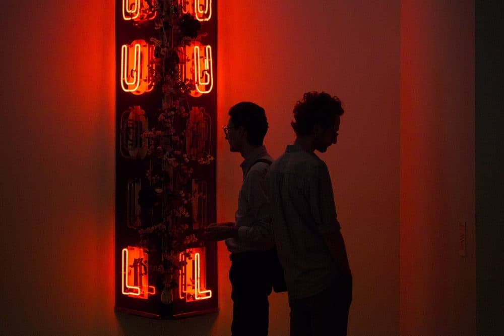 Two museum patrons view the neon sign "Radha Liquorsoul." (Jesse Costa/WBUR)