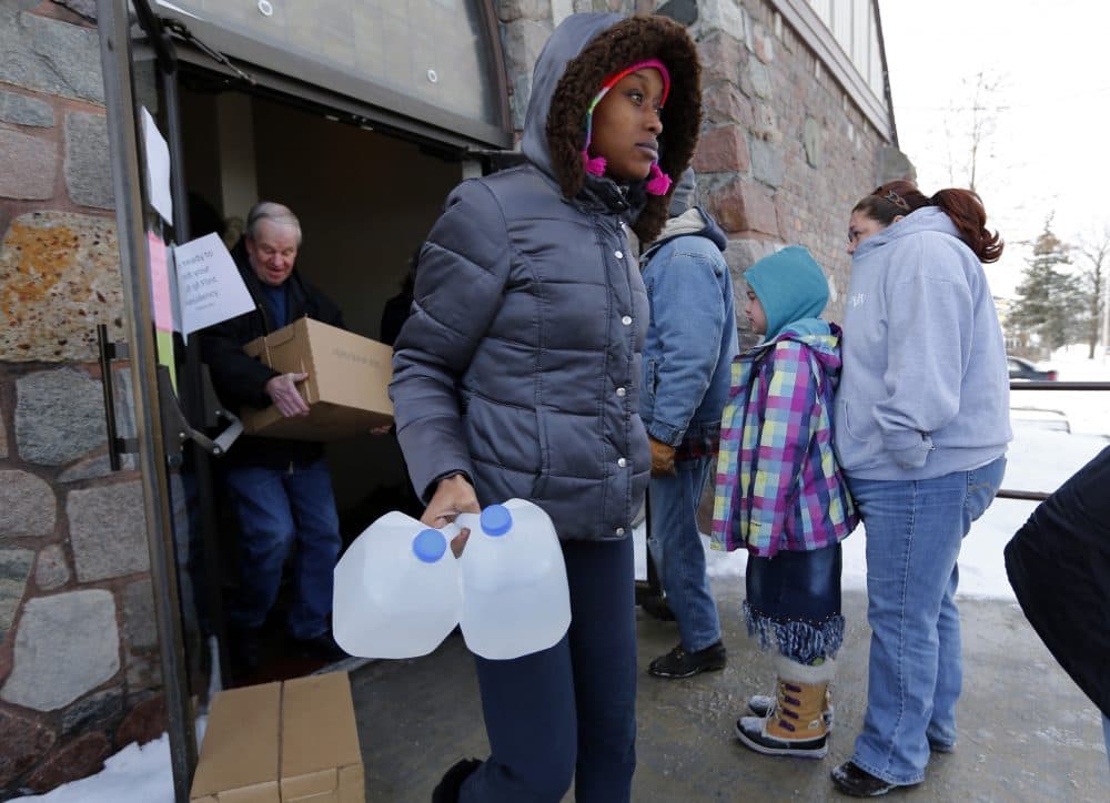 A woman carries free water being distributed in Flint, Mich., in Feb. 2015 after the city was found to be in violation of the Safe Drinking Water Act. (Paul Sancya/AP)
