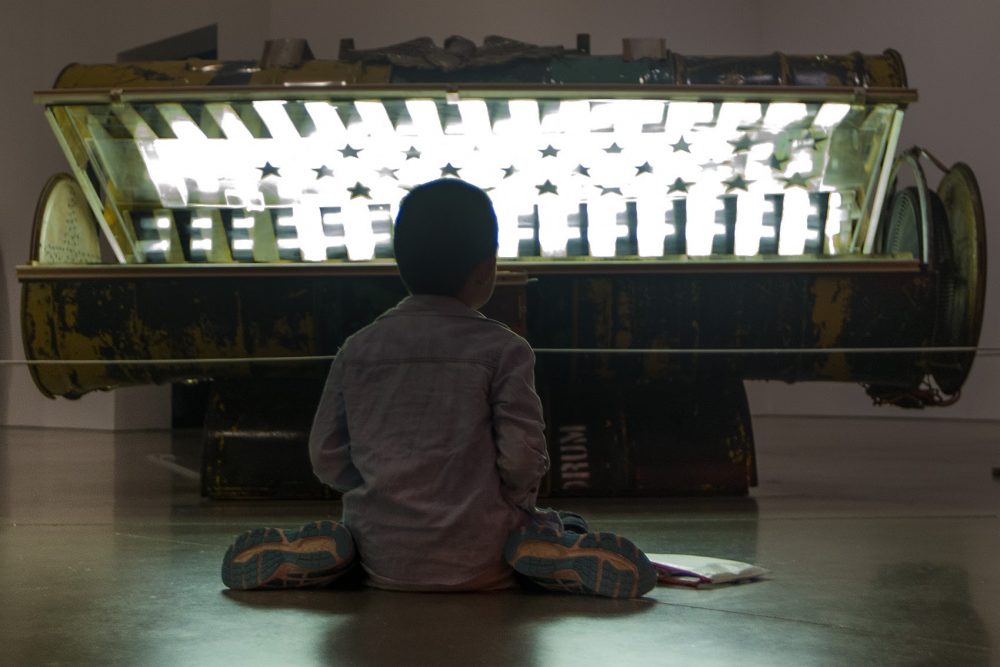 A 9-year-old boy colors on the floor in front of Nari Ward's "Tanning Bed" at the ICA. (Jesse Costa/WBUR)