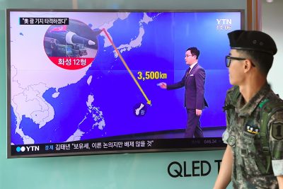 A South Korean soldier walks past a television screen showing a graphic of the distance between North Korea and Guam at a railway station in Seoul on Aug. 9, 2017. (Jung Yeon-Je/AFP/Getty Images)
