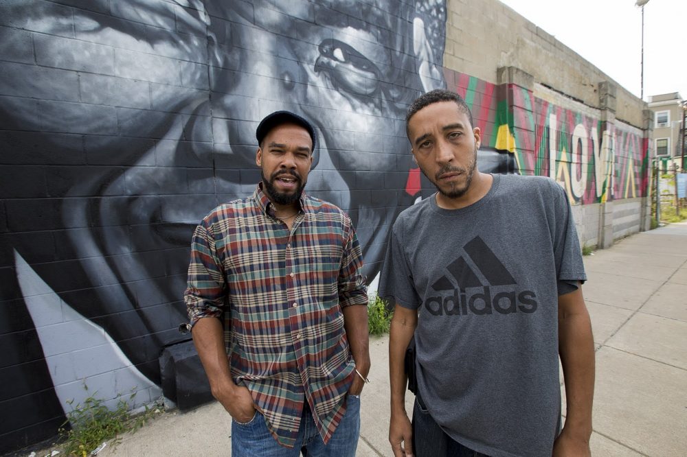 Artist Thomas "Kwest" Burns and activist Jamarhl Crawford stand in front of the "Roxbury Love" mural on Warren Street. (Jesse Costa/WBUR)
