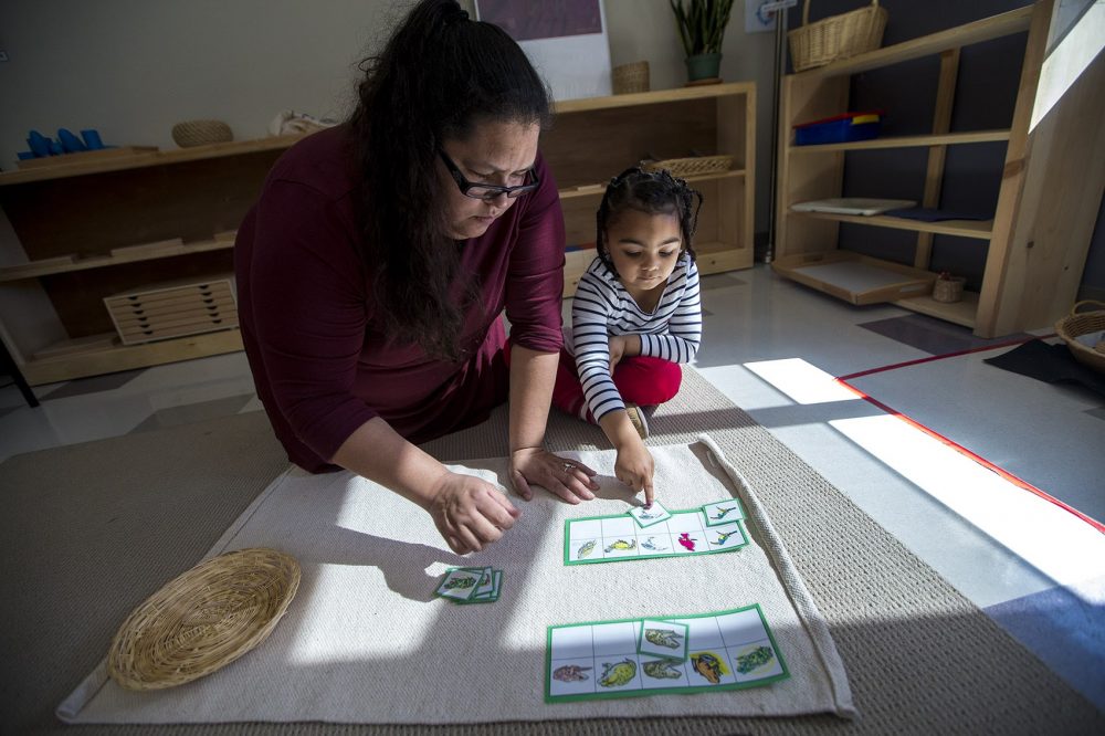 Tia Pocknett assists a student with a matching game involving images of birds and frogs. (Jesse Costa/WBUR)