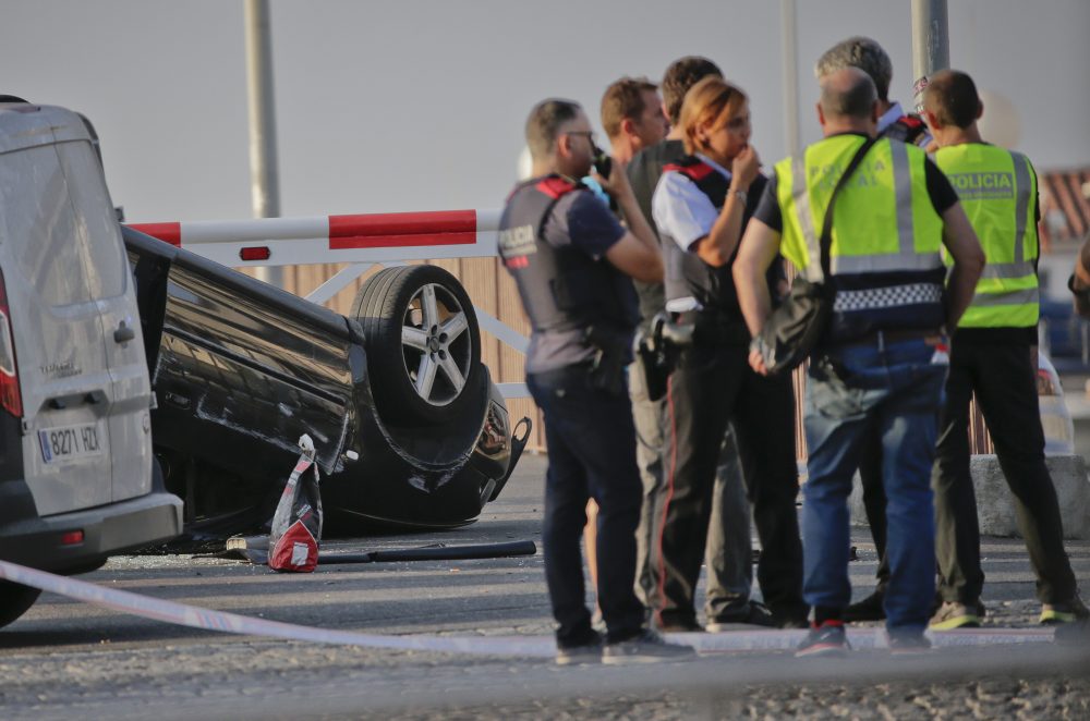 Police officers speak near an overturned car at the spot where terrorists were intercepted by police in Cambrils, Spain, Friday. (Emilio Morenatti/AP)