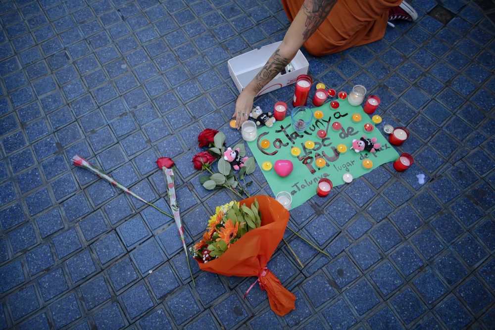 A woman places a candle next to a paper that reads "Catalunya - place of peace" in Barcelona Friday. (Manu Fernandez/AP)