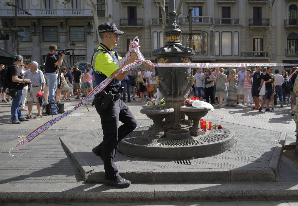 A police officer removes a no access police tape along Barcelona's Las Ramblas promenade on Friday. (Manu Fernandez/AP)