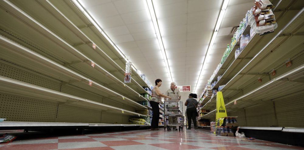 Shoppers pass empty shelves along the bottled water aisle in a Houston grocery store Thursday. (David J. Phillip/AP)