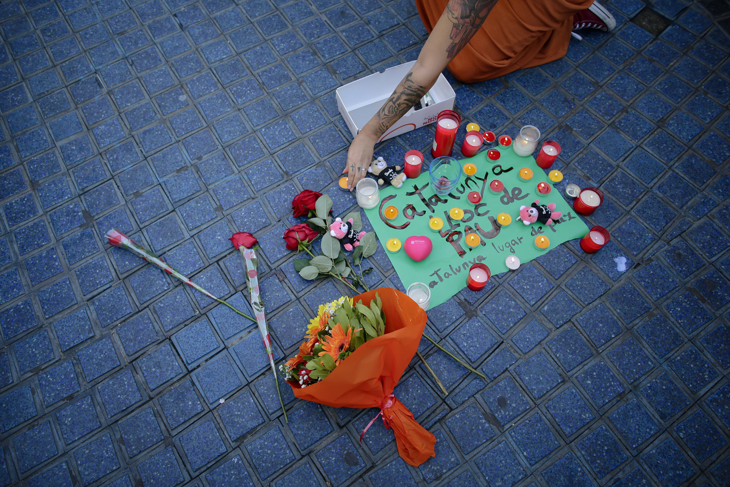 A woman places a candle next to a paper that reads "Catalunya - place of peace" in Las Ramblas, Barcelona, Spain, Friday, Aug. 18, 2017. (Manu Fernandez/AP)