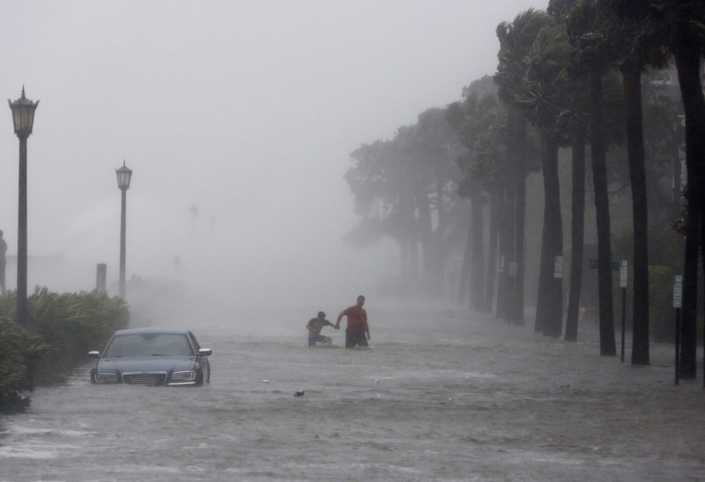 This Sept. 11, 2017 file photo shows pedestrians walking by on a flooded street as Tropical Storm Irma hits Charleston, S.C. (Mic Smith/AP)