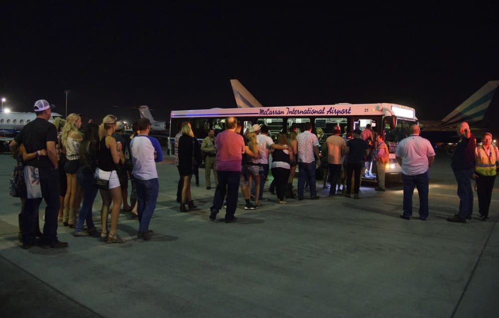 Police escort people to an evacuation bus after hiding inside the Sands Corporation plane hangar. (Al Powers/Invision/AP)