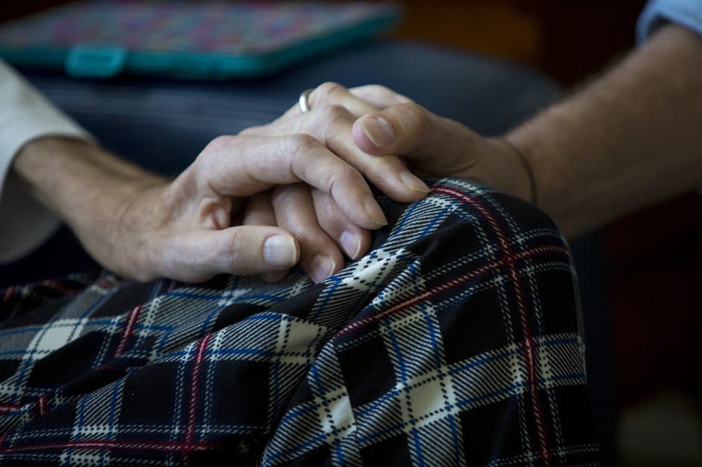Hoffman holds the hand of ALS patient Don Vieweg. (Jesse Costa/WBUR)
