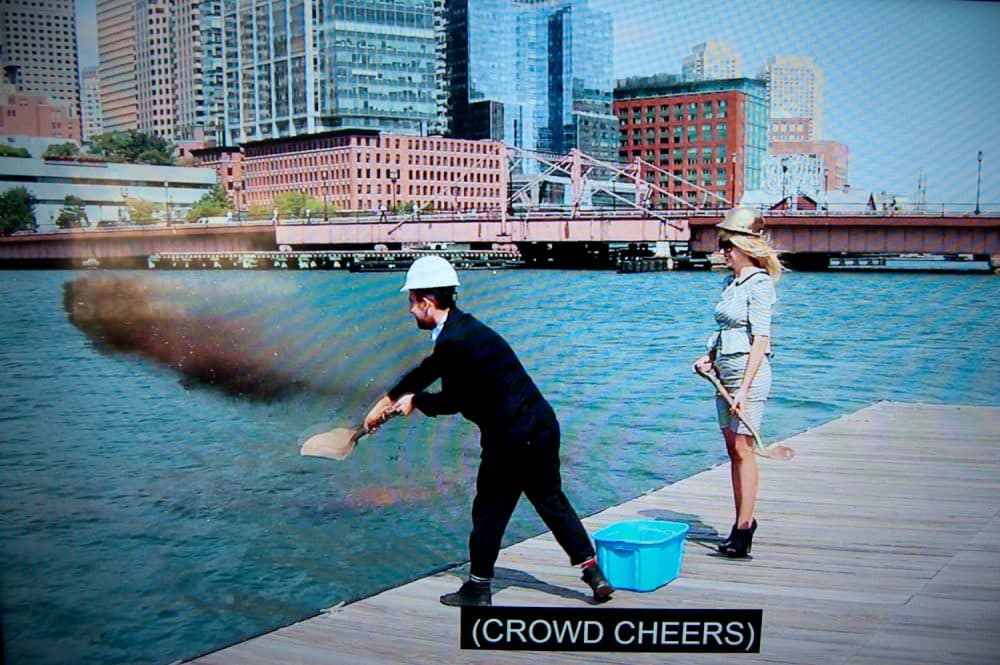 Pat Falco shovels dirt into Boston's Fort Point Channel in a video purporting to show the groundbreaking of the "Luxury Waters" condo tower. (Greg Cook/WBUR)
