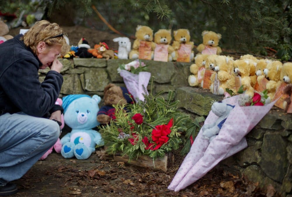 Cheryl Girardi, of Middletown, Conn., kneels beside 26 teddy bears, each representing a victim of the Sandy Hook Elementary School shooting, at a sidewalk memorial, Sunday, Dec. 16, 2012, in Newtown, Conn. A gunman walked into Sandy Hook Elementary School in Newtown Friday and opened fire, killing 26 people, including 20 children.(David Goldman/AP)