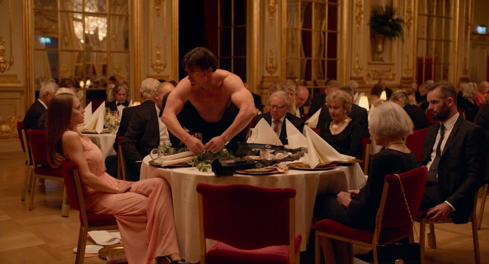 Terry Notary (pictured on the table) plays a performance artist in "The Square." (Courtesy Magnolia Pictures)