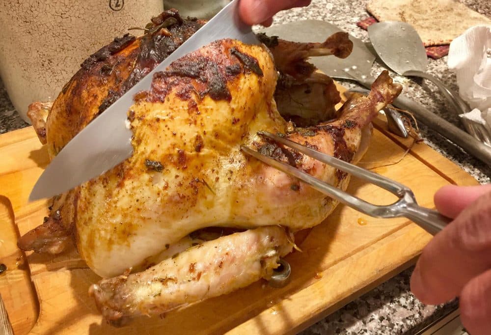 Kathy slices a roast turkey just out of the oven. (Kathy Gunst for Here & Now)