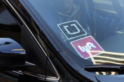 A driver displaying Lyft and Uber stickers on his car. (AP Photo/Richard Vogel)