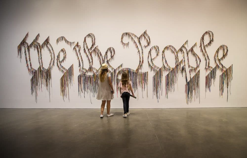 Visiting the ICA on vacation from Columbia, Maria Alejandra Garcia Velez and her daughter Maria Jose Cortes Garcia, 9, approach the shoelace work by Nari Ward, "We the People." (Jesse Costa/WBUR)