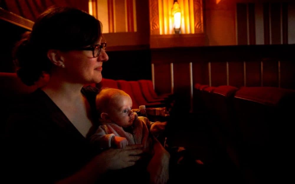 As the lights go down Leah Hampton and her 11-week-old son Will settle down to watch "Faces, Places." (Robin Lubbock/WBUR)