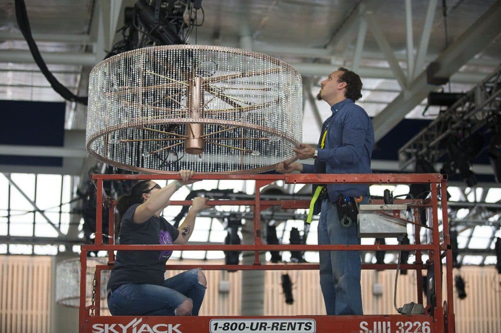 Aurelia Lyman, left, and Taylor Hansen position one of the six chandeliers in the rink-turned-opera house. (Jesse Costa/WBUR)