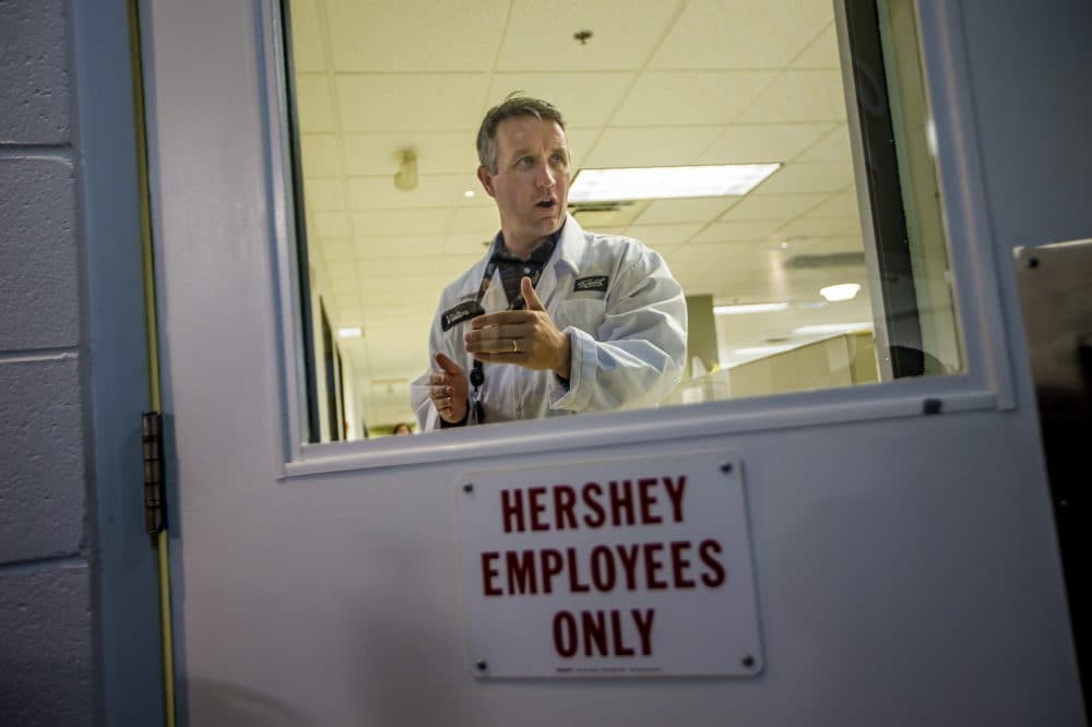 Jordan Sinclair, vice president of communications for Canopy, speaks to another employee behind a door with one of the many signs left behind by The Hershey Company before moving to Mexico. (Jesse Costa/WBUR)