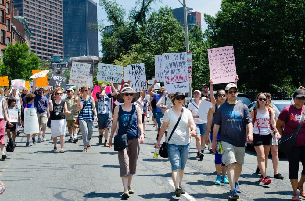 Demonstrators carry signs protesting ICE and the now-halted family separation policy. (Elizabeth Gillis/WBUR)