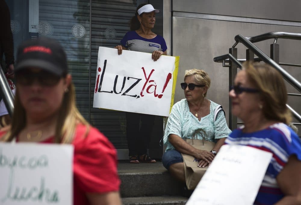 In this May 15, 2018 photo, residents from Yabucoa, where many are still without power, protest outside the Electric Power Authority office, demanding the reestablishment of electricity eight months after Hurricane Maria, in San Juan, Puerto Rico. The sign reads in Spanish "Light now!" (Carlos Giusti/AP)