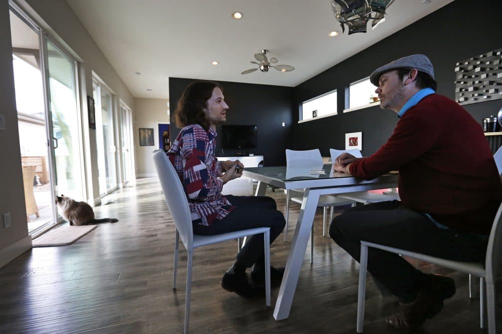 In this March 13, 2014 photo, Dave Mullins, left, and his husband Charlie Craig play cards and talk after a work day, at their home in Westminster, Colo. The couple filed a legal complaint with the Colorado Civil Rights Commission against a Denver-area baker who refused to make a wedding cake for the two men, based on his religious beliefs. (Brennan Linsley/AP)
