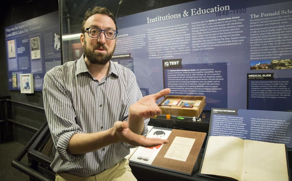 Gann Academy history teacher Alex Green talks with students at the "Disability History of the United States" exhibit. (Robin Lubbock/WBUR)