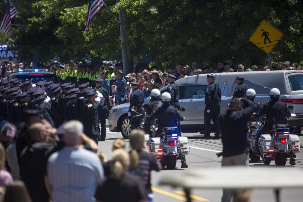 Poilce salute as the funeral procession leaves the church. (Jesse Costa/WBUR)
