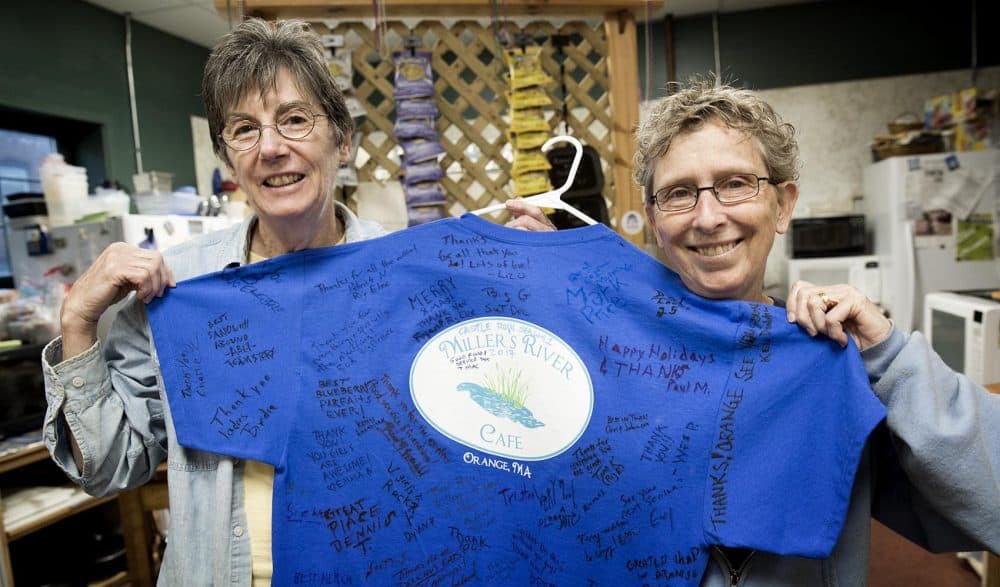 Kris Burns and Jeanie Miller hold up a T-shirt signed by members of the "Castle Rock" crew who visited their cafe in Orange during filming. (Robin Lubbock/WBUR)